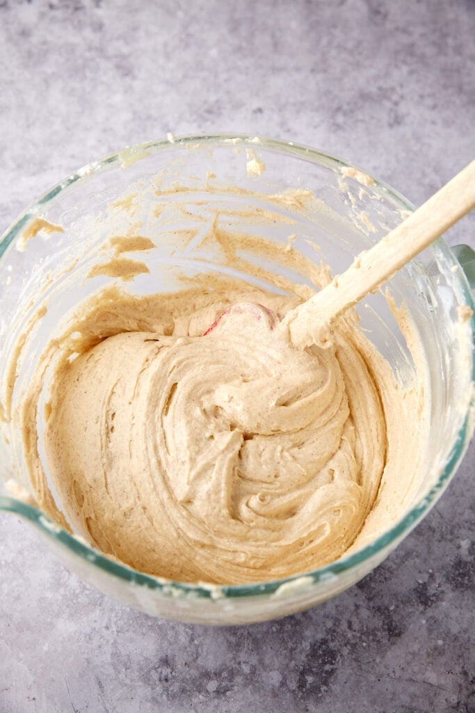 blackberry jam cake batter before the blackberries in a glass bowl with a spatula.