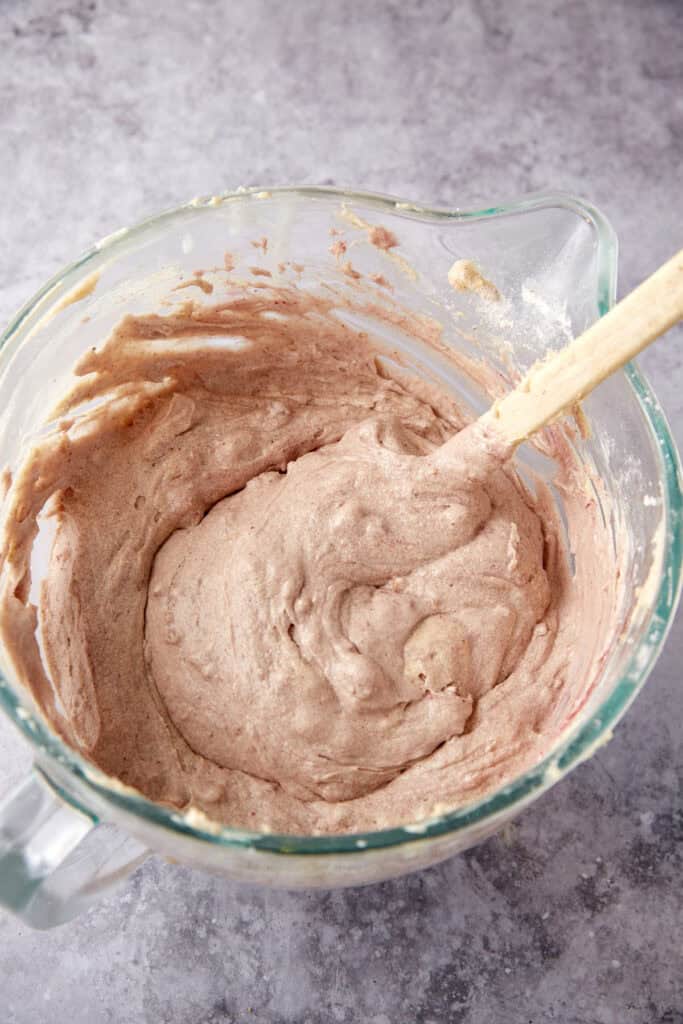 blackberry jam cake batter in a glass bowl with a spatula.