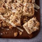close up of glazed crumb cake on a wooden cutting board.