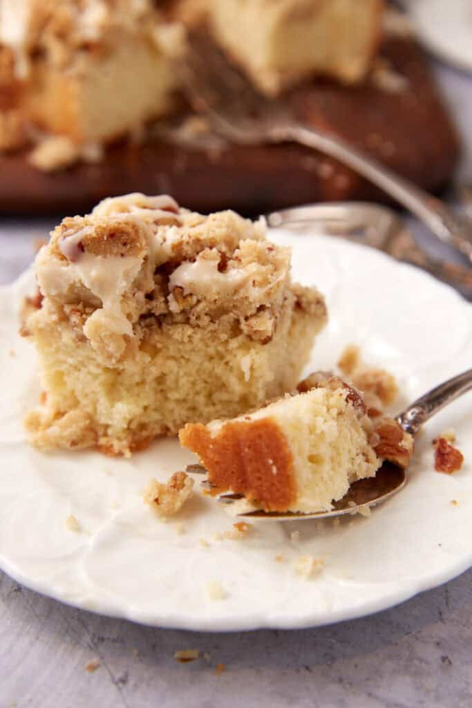 crumb cake on a white plate with a fork and a bite taken out of the cake.