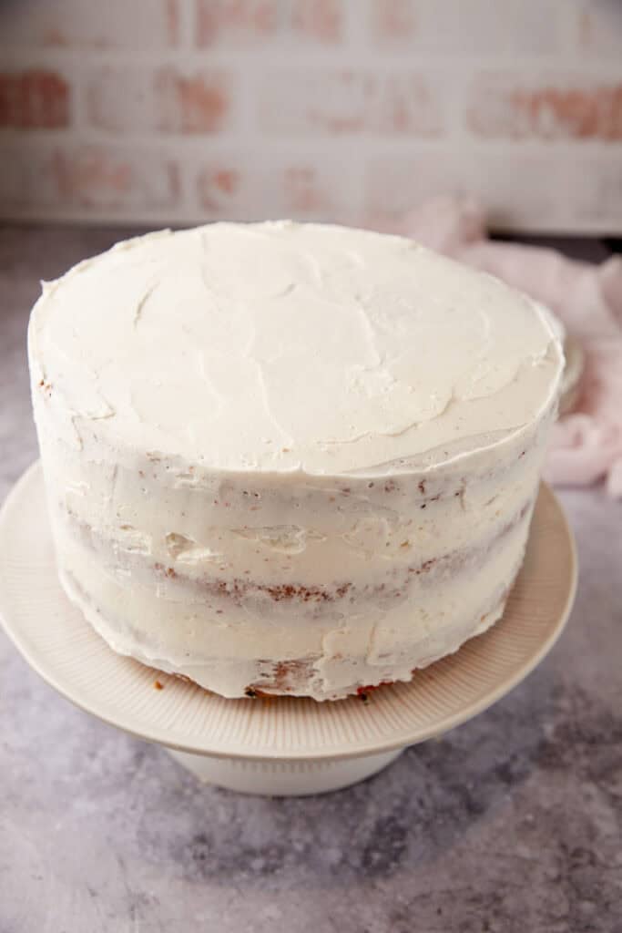 frosted confetti cake on a white cake stand.