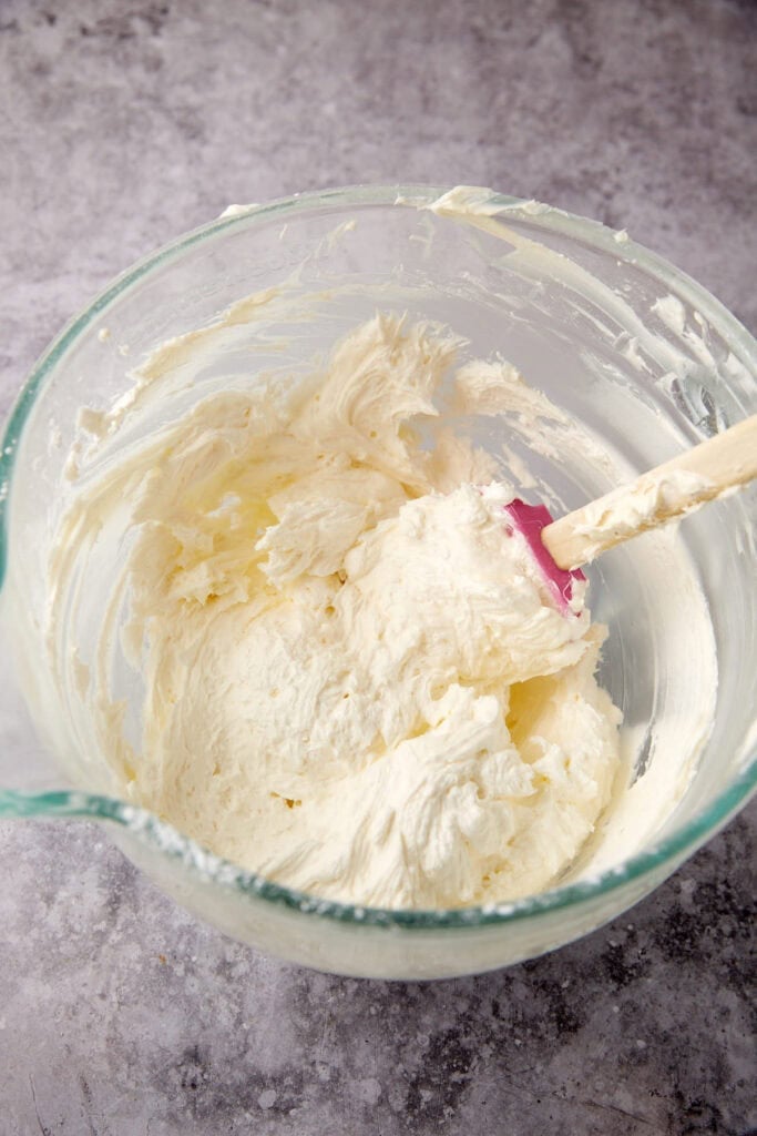 vanilla buttercream frosting in a glass bowl with a spatula.