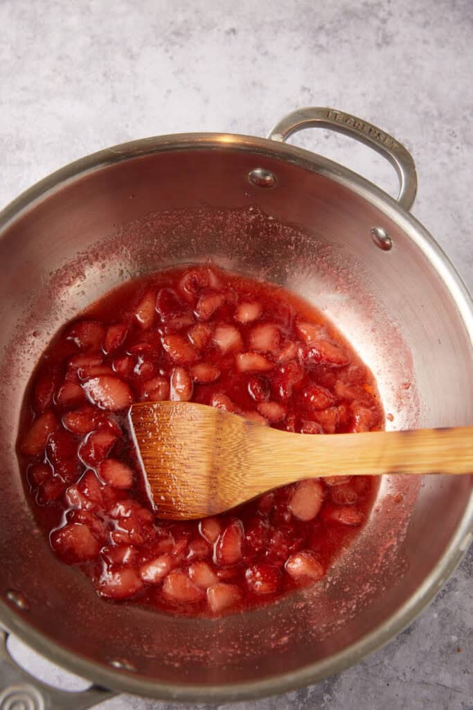 strawberry syrup in a saucepan with a wooden spoon.