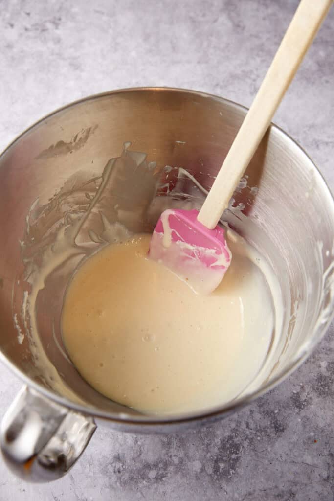 condensed milk and cream cheese in a metal bowl with a spatula.