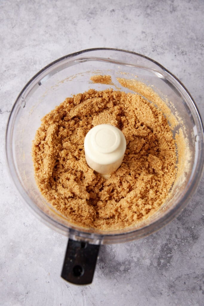 graham cracker crust ingredients being pulsed in a food processor.