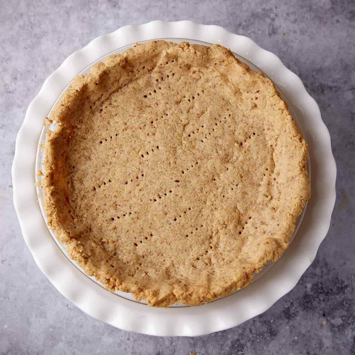 walnut pie crust on top of a white cake stand.