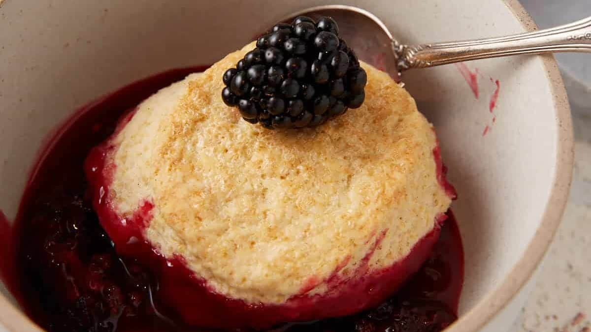 A bowl of blackberry cobbler with a biscuit on top.