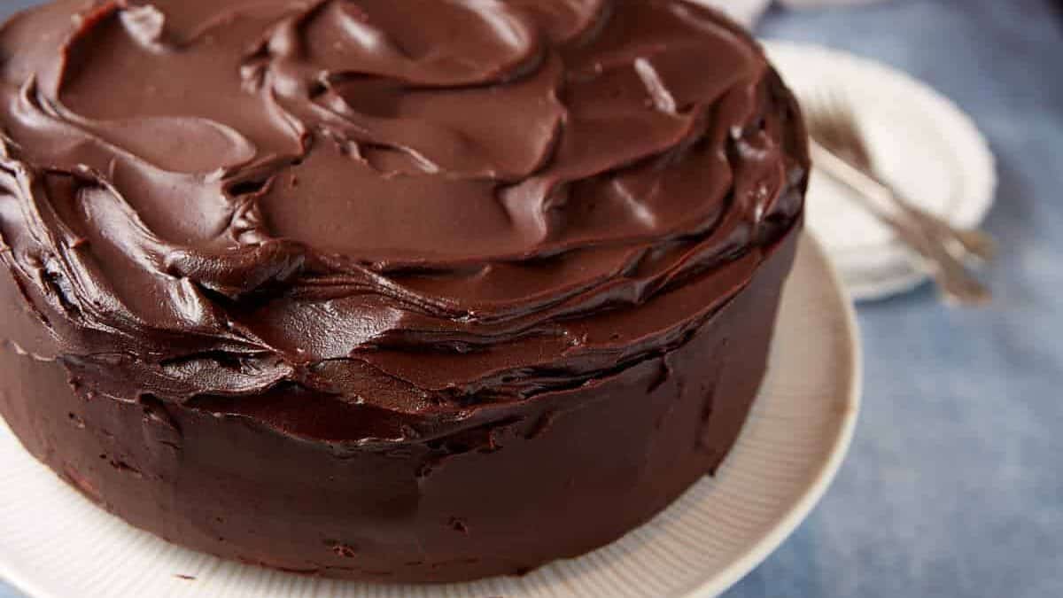 A frosted chocolate layer cake next to a cake server.
