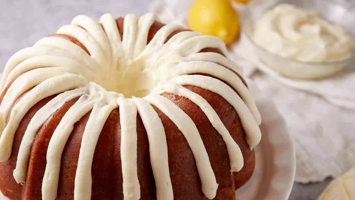 frosted lemon bundt cake on a white plate.