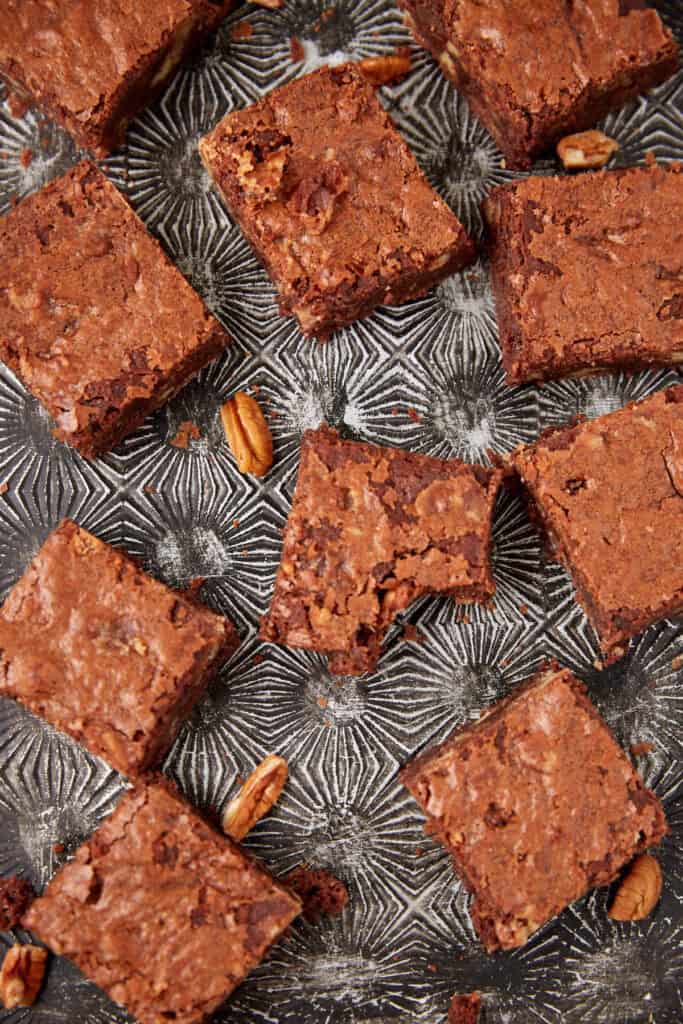 praline brownies on a glass serving dish and a bite taken out of one.