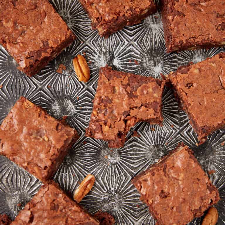 praline brownies on a glass serving dish and a bite taken out of one.