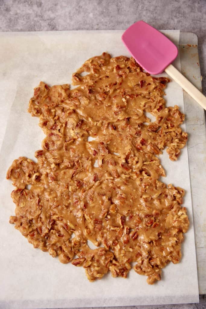 pralines being spread out on a cutting board with a spatula.