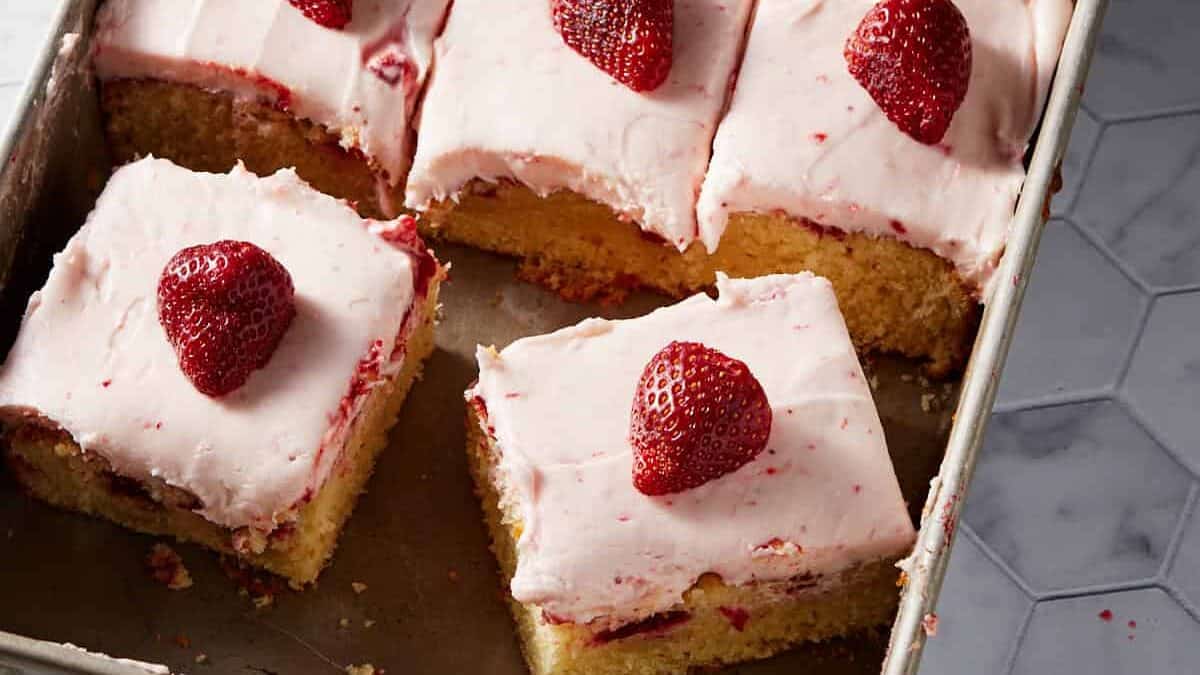 strawberry poke cake cut into slices in the pan.