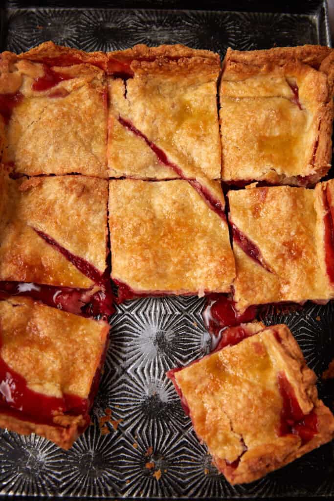 A square strawberry slab pie with a slice missing.