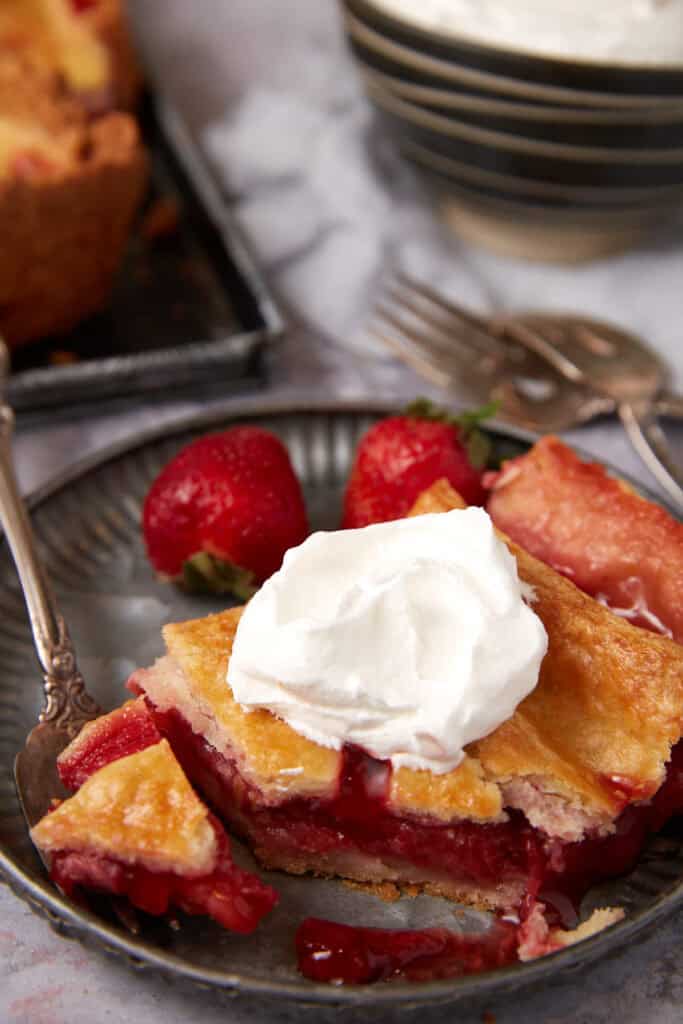 A slice of strawberry pie with whipped cream on top.