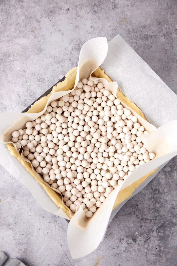A square of parchment paper filled with pie weights.