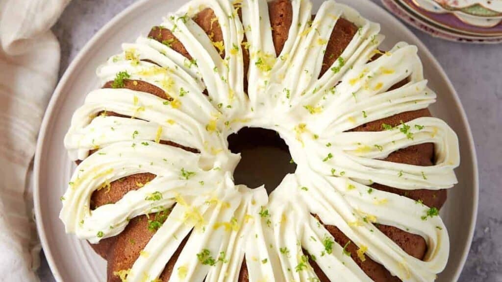 A bundt cake with white frosting and a slice taken out.