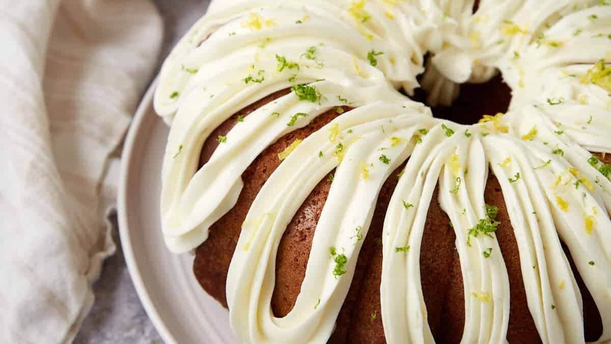 A bundt cake with frosting and lime slices.