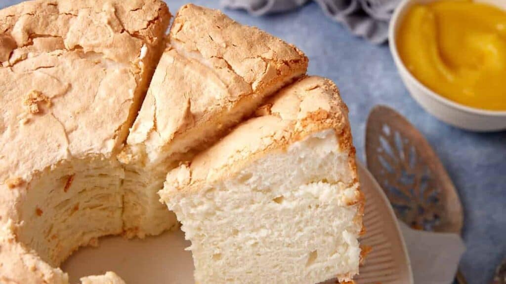 Angel food cake on a cake stand cut into slices.