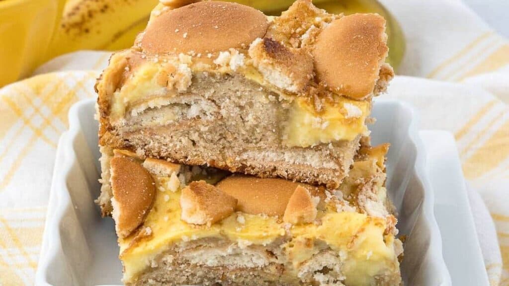 stacked banana pudding brownies in a white dish.