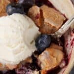 A bowl of blueberry cobbler with ice cream.