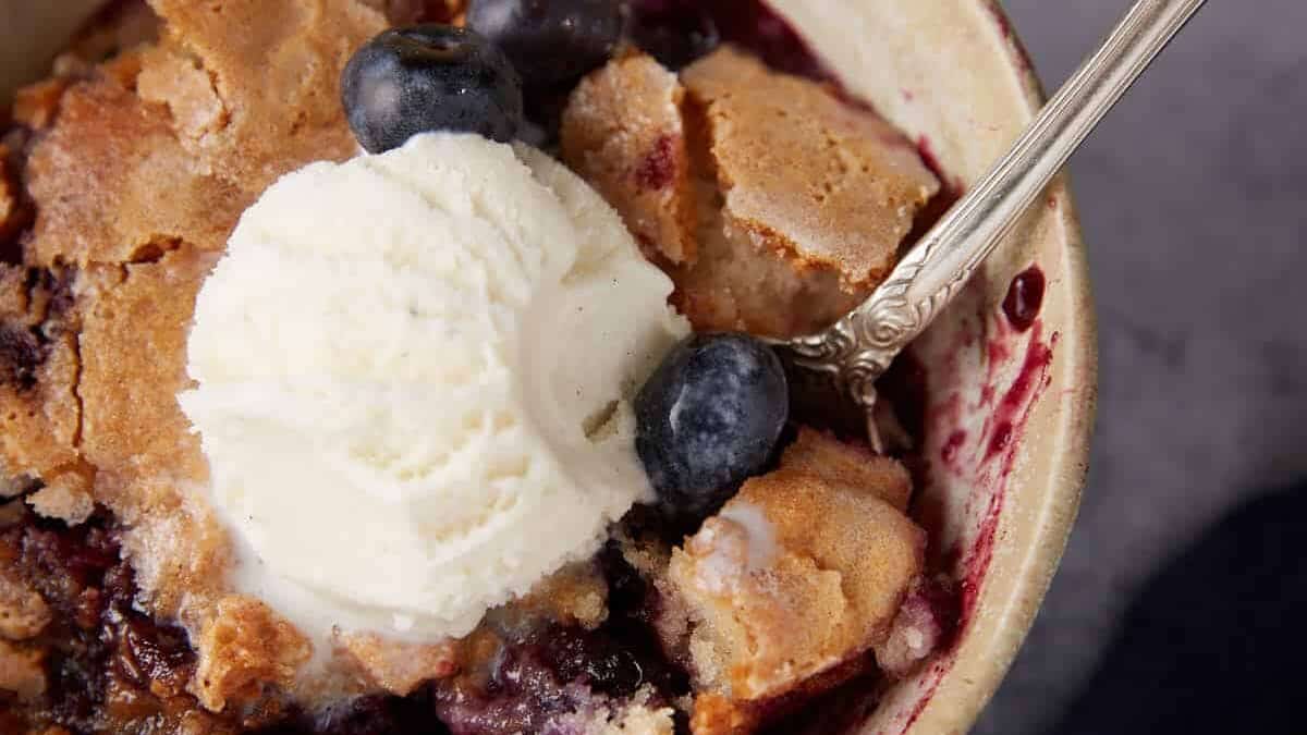 A bowl of blueberry cobbler with ice cream.