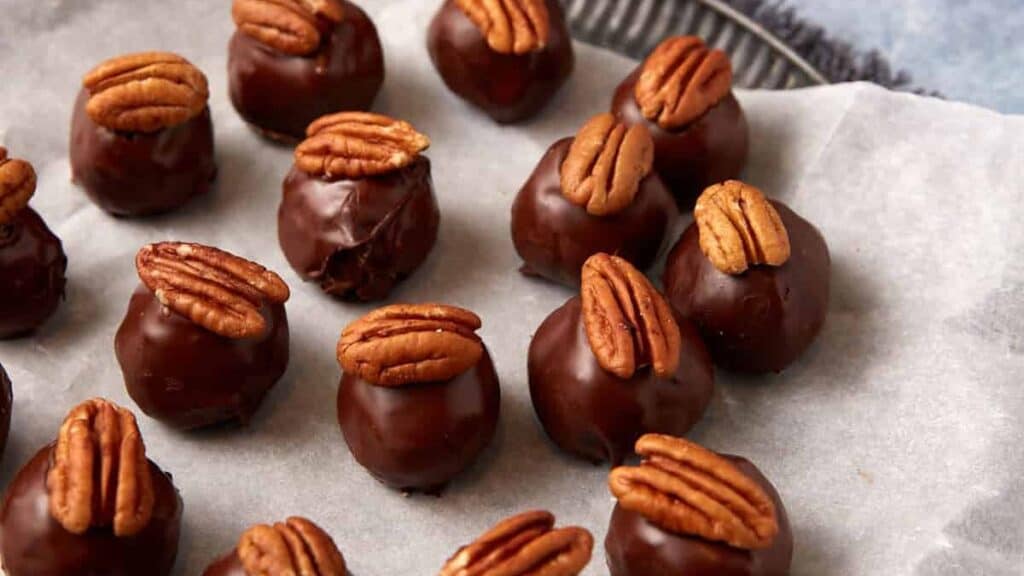 Pecan topped bourbon balls on parchment paper.