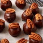 Pecan topped bourbon balls on parchment paper.