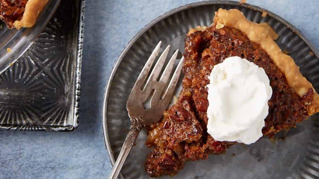 A slice of chocolate pecan pie with whipped cream on top.