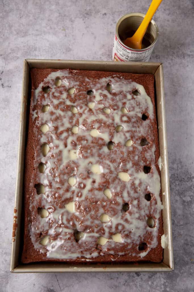 chocolate cake with holes poked into it with sweetened condensed milk on top.