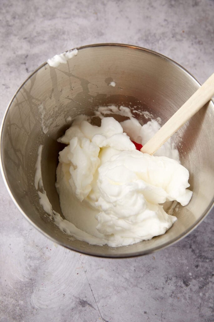 egg whites in a metal bowl with a spatula.