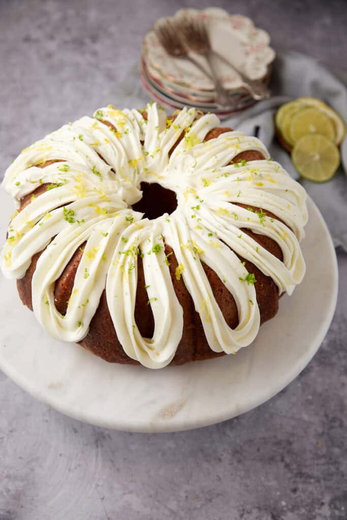7-up cake with lemon lime frosting on a white cake stand.
