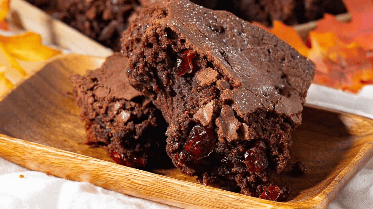 stacked moist brownies on a brown plate.