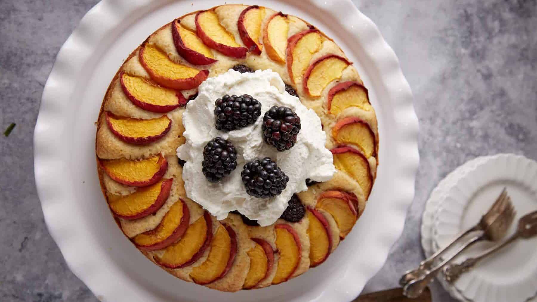 A peach and blackberry cake topped with whipped cream.