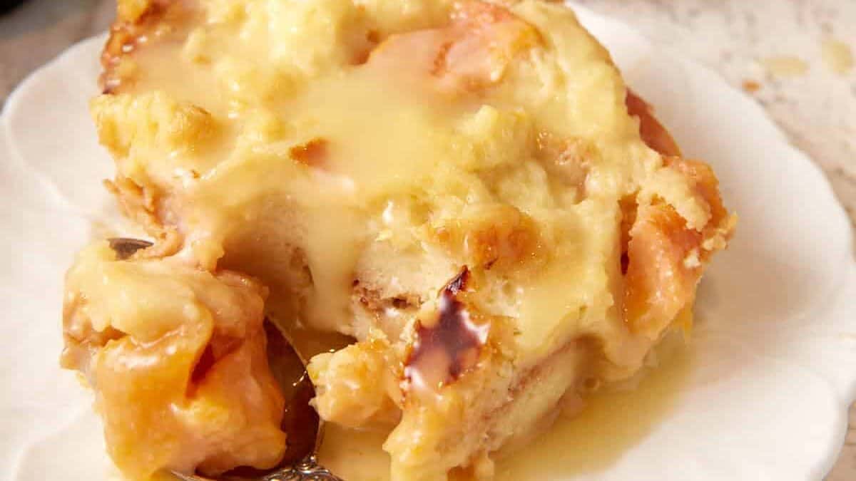 A serving of peach bread pudding on a plate with a fork.