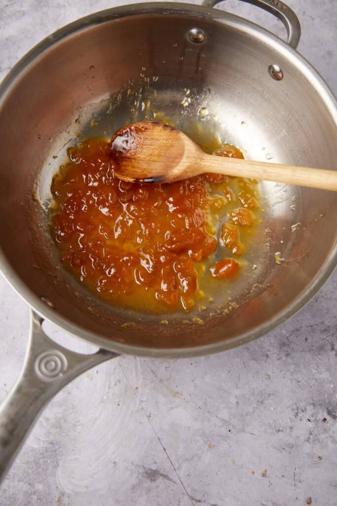 peach jam in a saucepan with a wooden spoon.