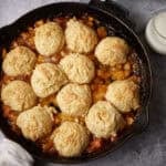 peach cobbler with biscuits in a skillet.