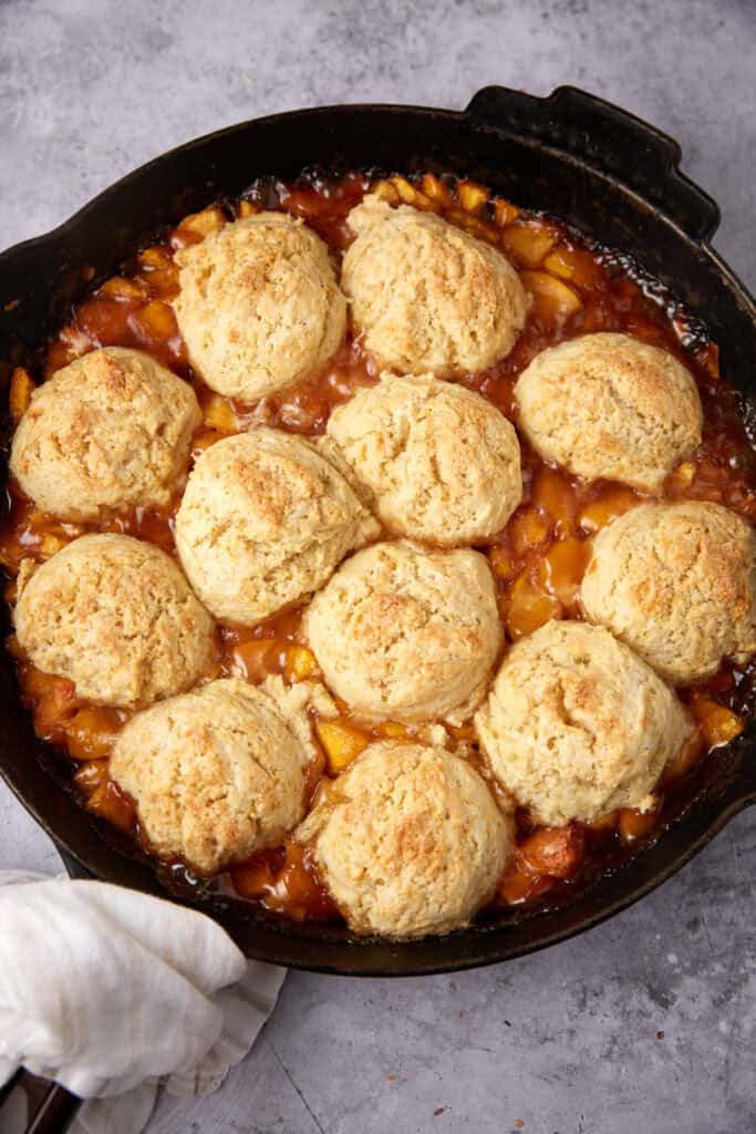 peach cobbler with biscuits in a skillet.