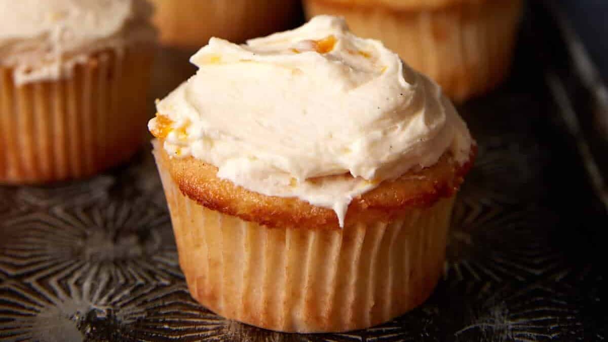 Frosted peach cupcakes on a platter.