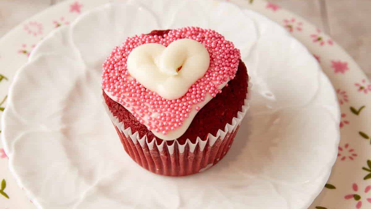 A single red velvet cupcake decorated with a heart.