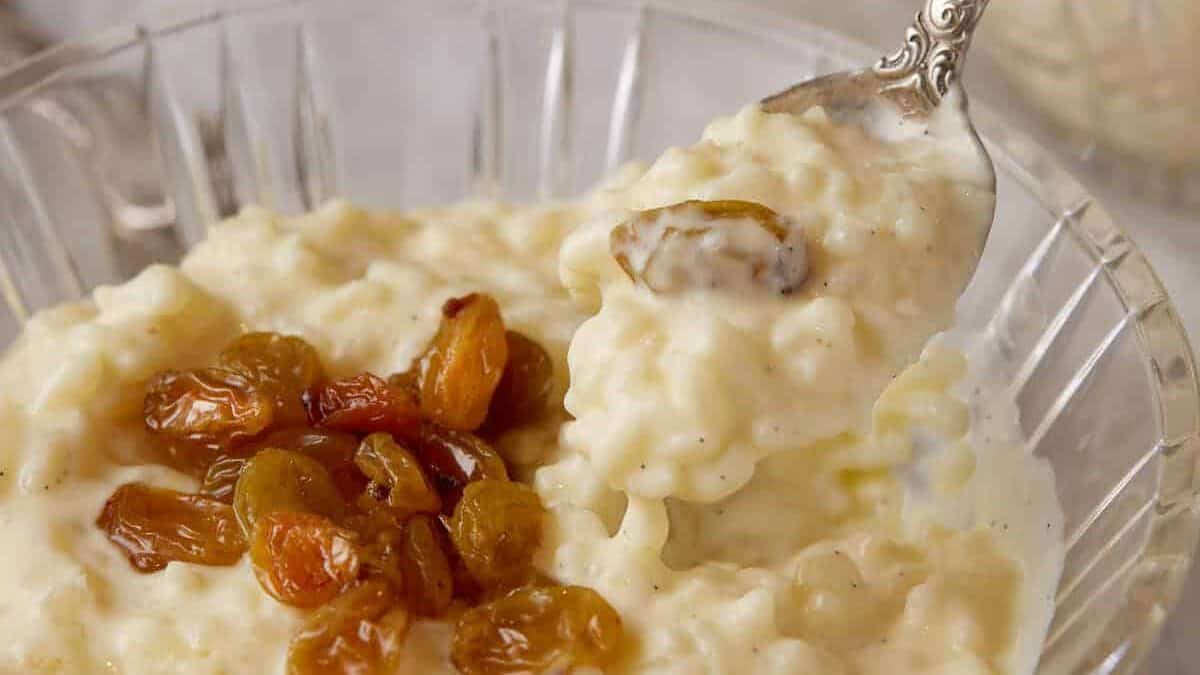 A spoon full of rice pudding with raisins.