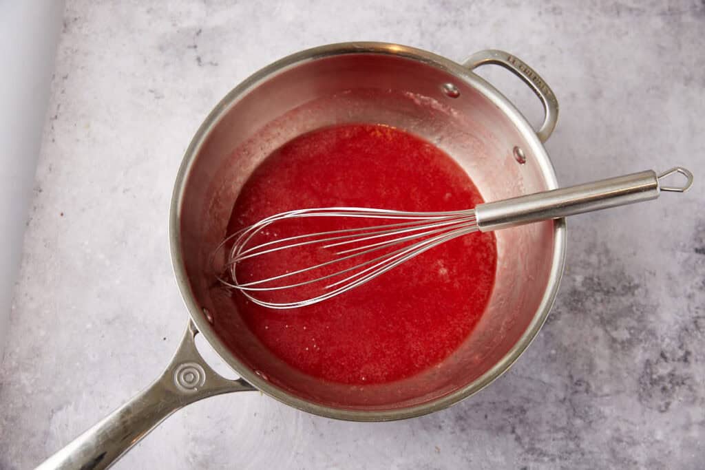 strawberry syrup in a saucepan with a whisk. 
