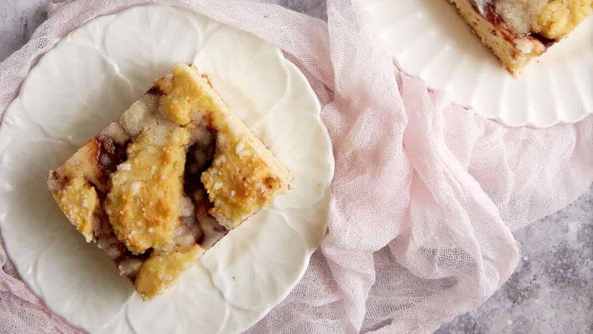 Three pieces of cake on white plates with pink napkin.