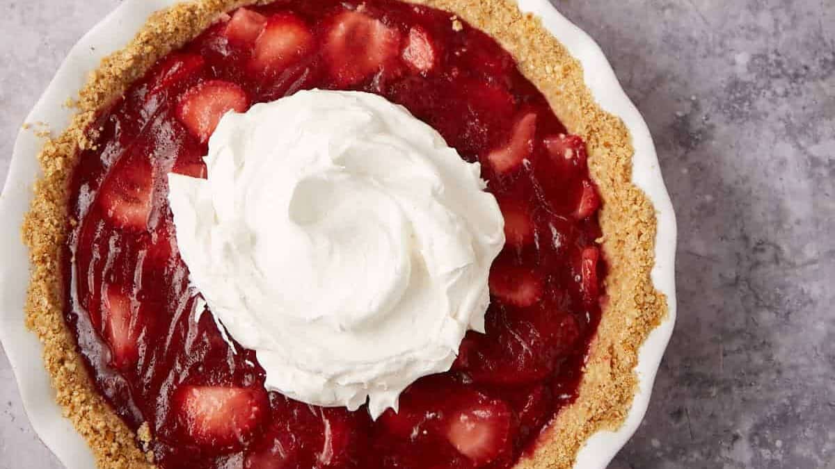 A strawberry pie topped with whipped cream.
