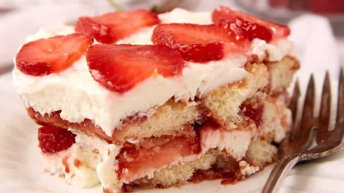 a slice of strawberry tiramisu on a white plate with a fork.