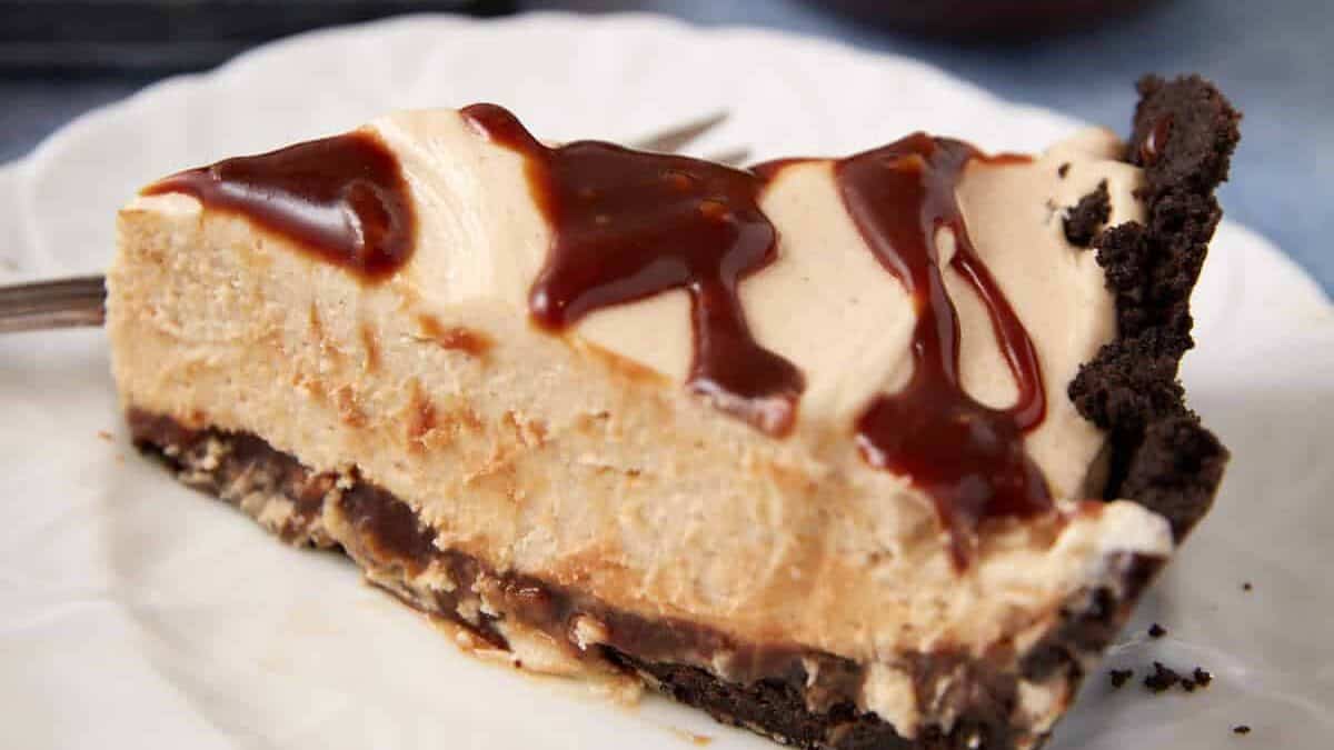 A single slice of turtle pie next to caramel sauce.