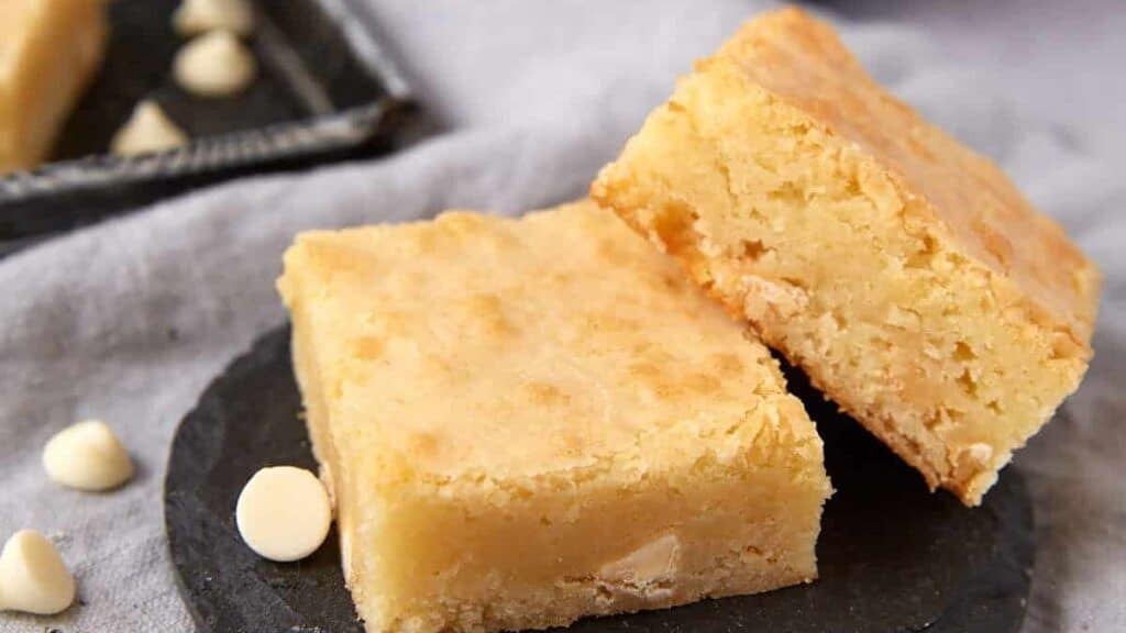 white chocolate brownies on a black plate.