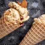 banana pudding ice cream in waffle cones with vanilla wafers in the background.