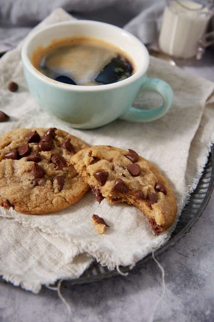 a cookie with a bite taken out next to a cup of coffee.