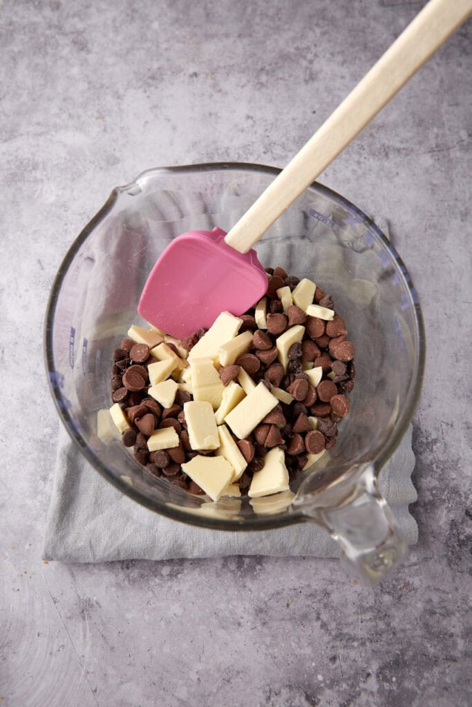 chopped chocolate in a glass mixing bowl with a spatula.